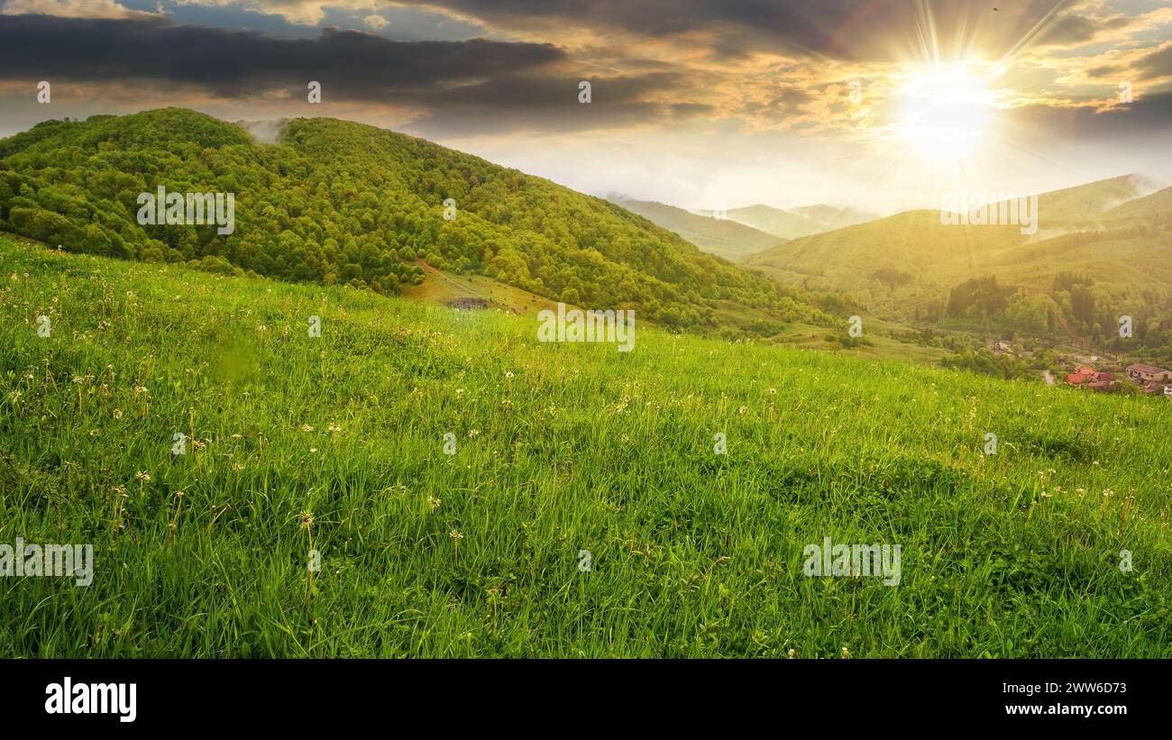 splendido paesaggio di campagna montuosa alla luce della sera. foresta su una collina al tramonto. villaggio nella valle Foto Stock