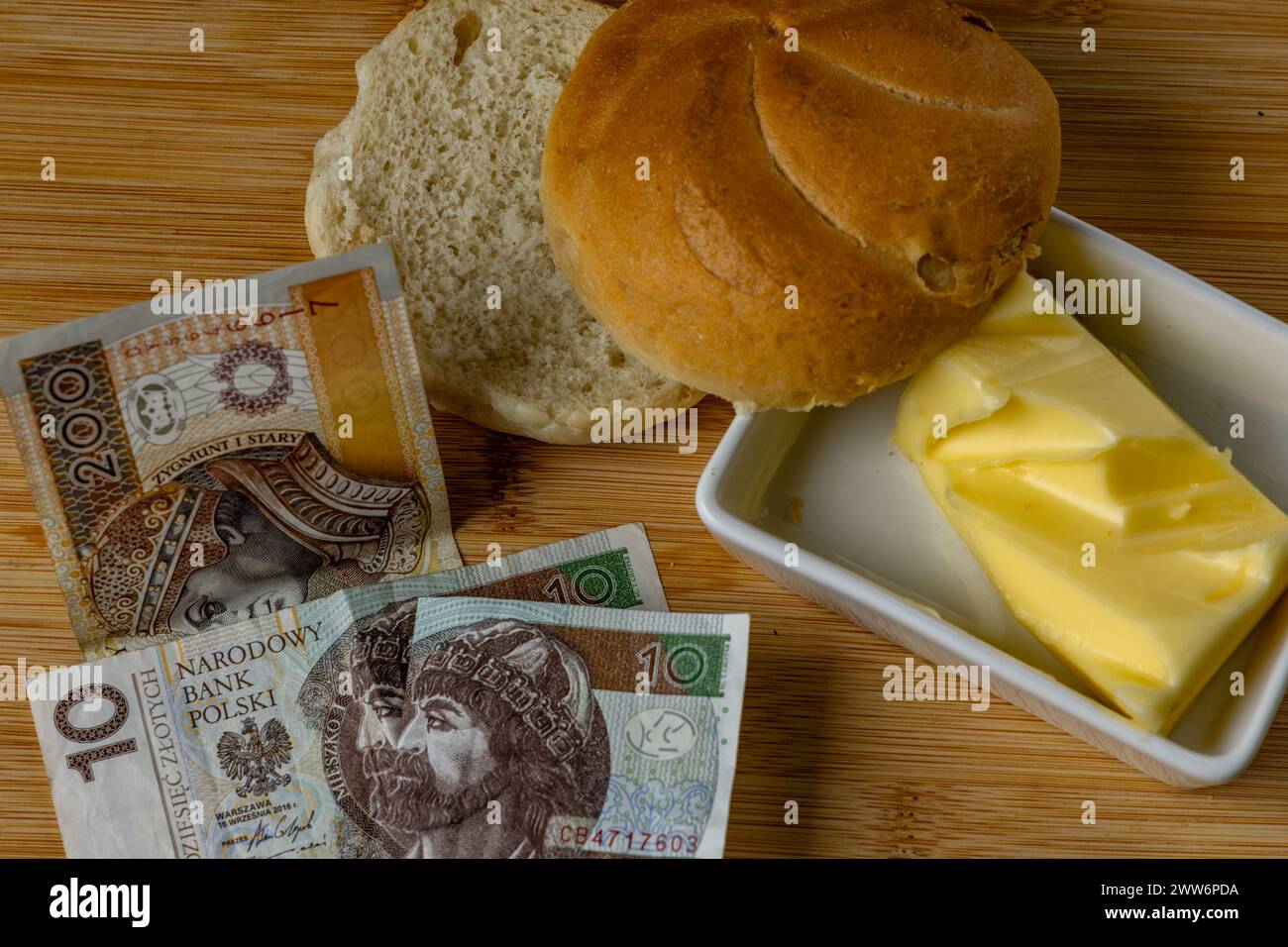 Aumento dei prezzi dei prodotti alimentari in Polonia, pane, burro su un tagliere, pomodori, salsicce, IVA sui soldi della Polonia alimentare Foto Stock