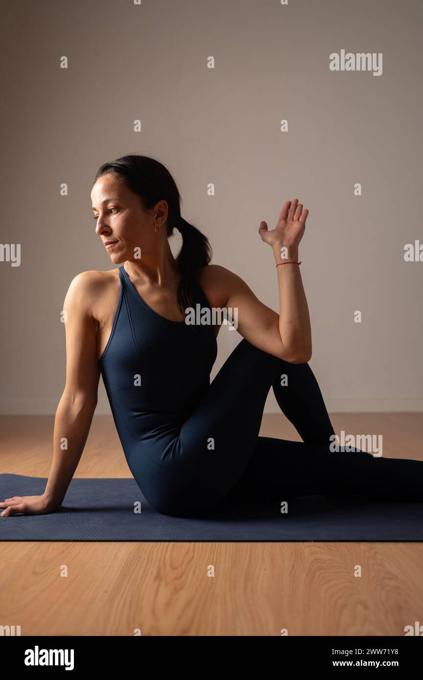 Scena di una donna che fa yoga in un salotto poco illuminata. Foto Stock