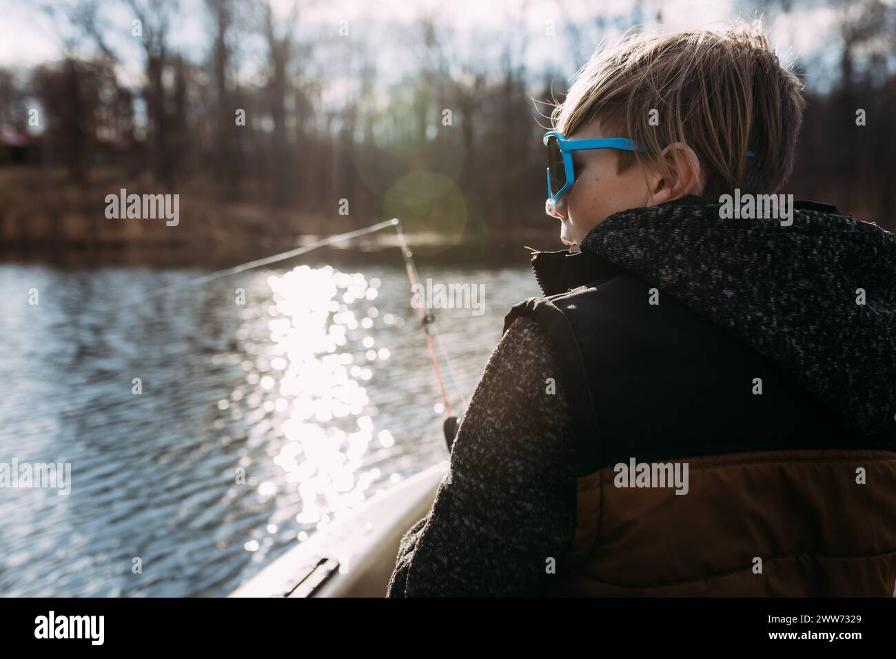 Ragazzo che pesca dal kayak sul lago in primavera Foto Stock