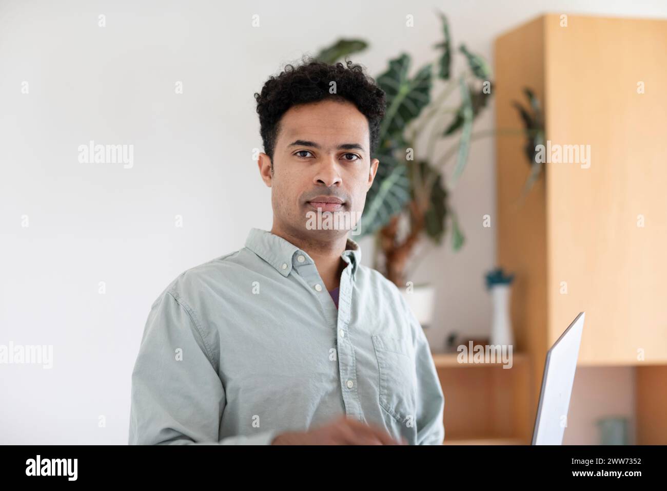 Giovane uomo, razza mista, con un portatile in ufficio Foto Stock