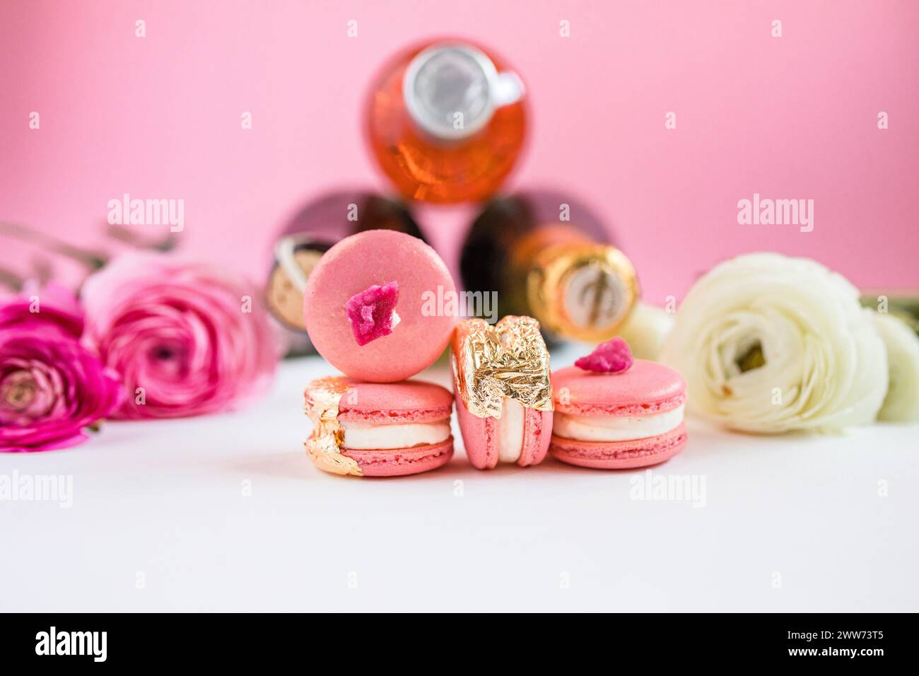 Macaron rosa ricoperti di foglie d'oro davanti allo champagne Foto Stock