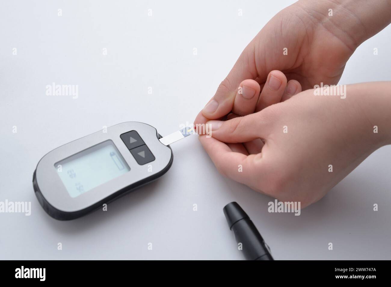 Applicazione del sangue dal dito alla striscia e dispositivo per la misurazione dei livelli di glucosio nel sangue. Concetto di monitoraggio della salute e gestione del diabete Foto Stock