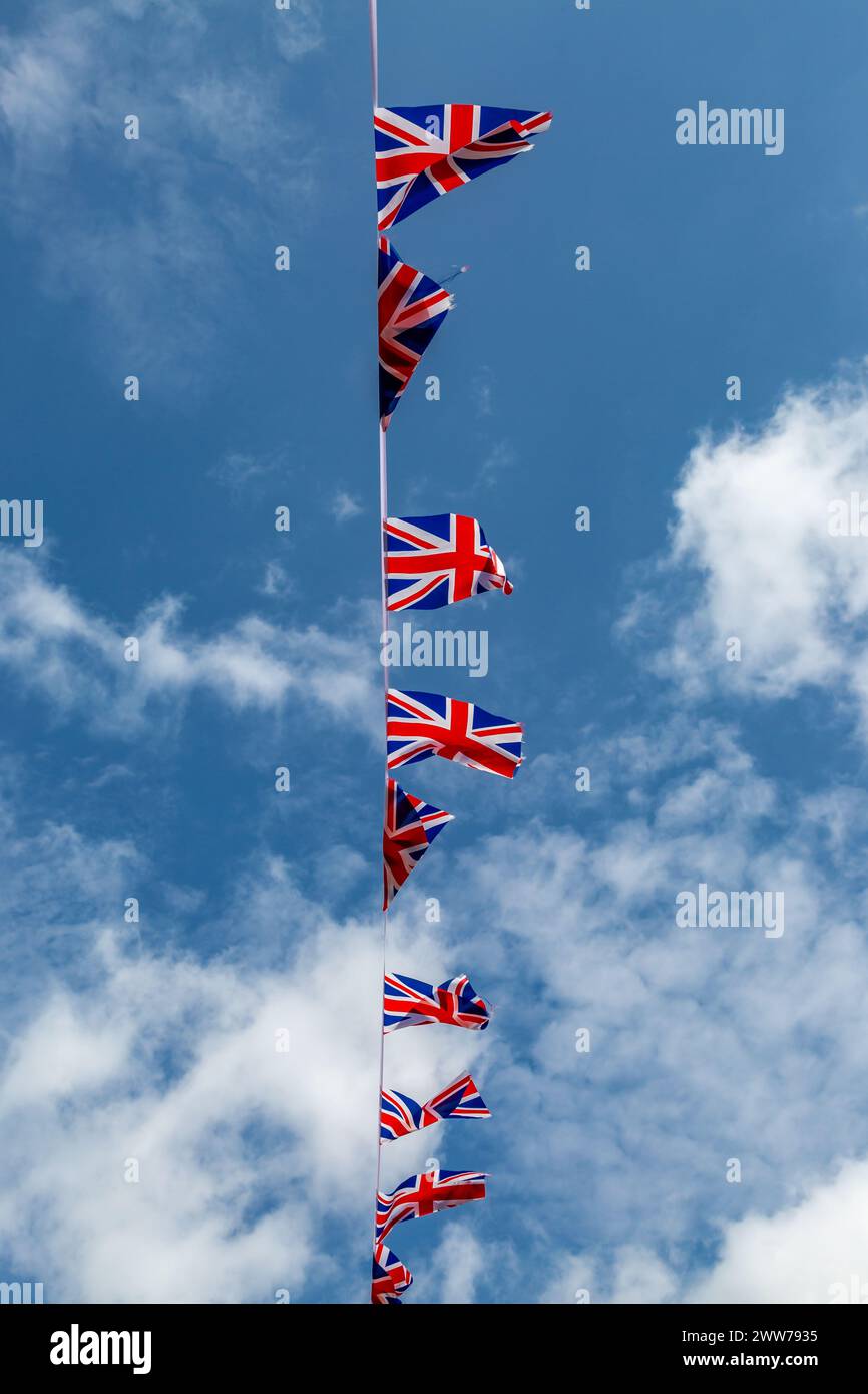 Una visuale ad angolo basso del patriottico Union Jack che soffia nel vento, con un cielo blu alle spalle Foto Stock
