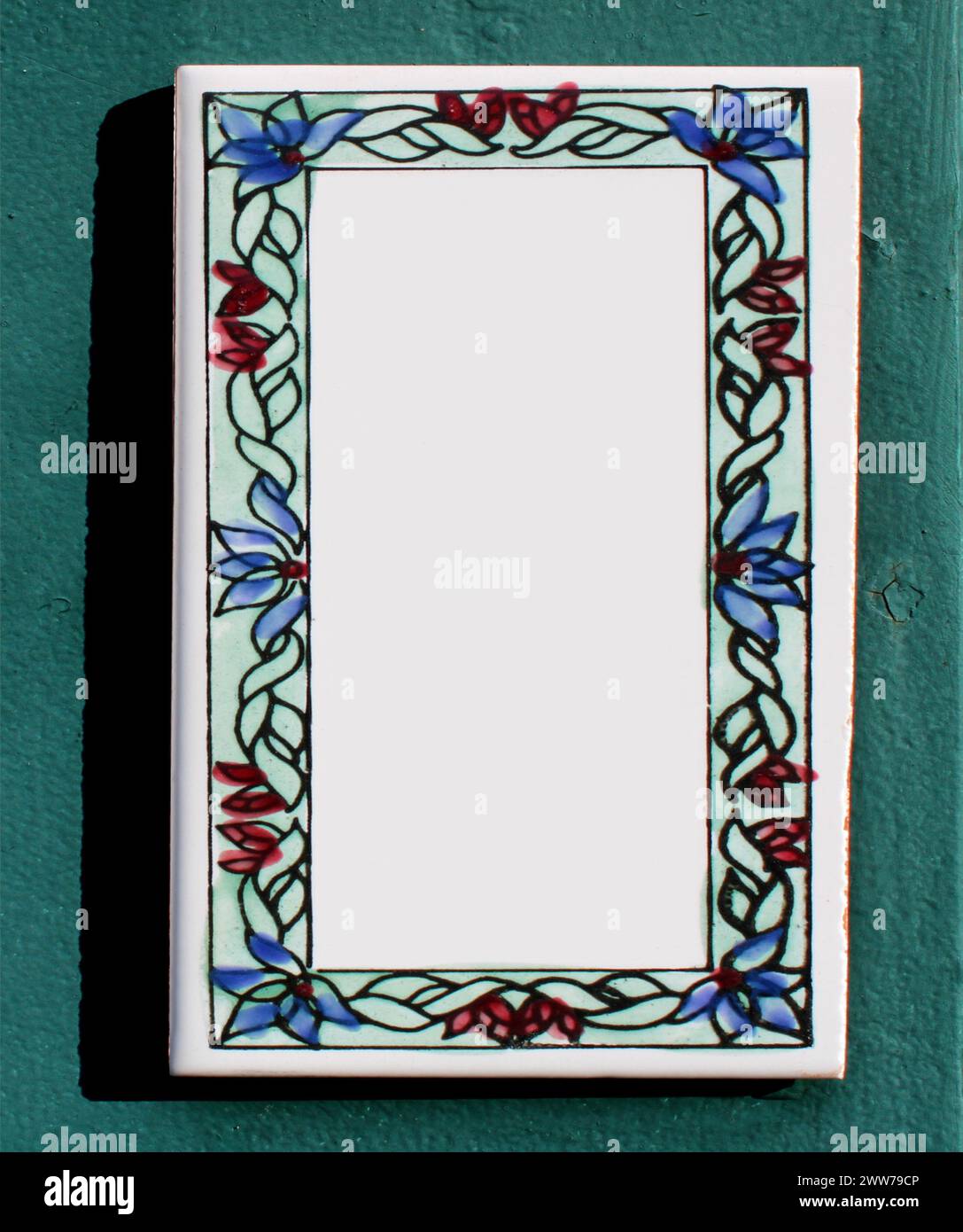 collage, insegne di ceramica in smalto o argilla su una rustica parete turchese. i fiori blu, rossi, le foglie verdi sono disegnati con un motivo. lastra di pietra rettangolare. Foto Stock