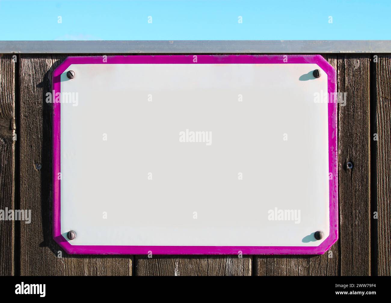 insegna collage, smalto, metallo o ceramica su una parete rustica in legno. cornice rosa, sotto un cielo turchese brillante. il sole splende, lastra di pietra rettangolare Foto Stock