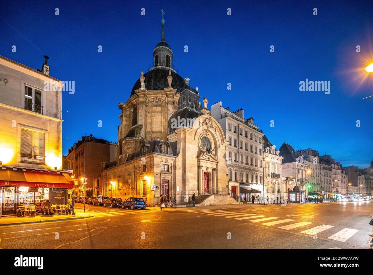 Il tramonto si adagia su Eglise Protestante du Marais con le luci della città che illuminano la strada. Foto Stock