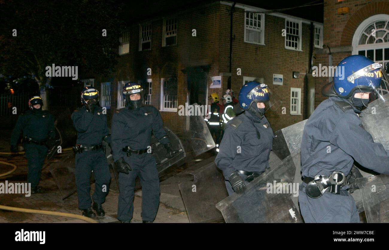 09/08/11..dopo che la violenza scoppia nel centro di Birmingham, gli ufficiali della squadra antisommossa depositano gli equipaggi dei vigili del fuoco mentre inumidiscono un incendio che ha gravemente danneggiato un p Foto Stock
