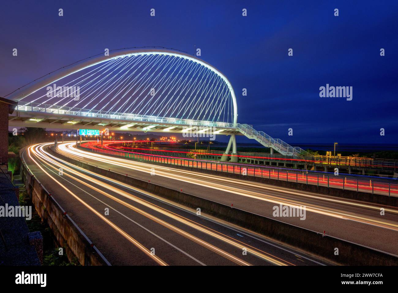 Pittoresca vista serale autunnale su un ponte a forma di arpa nel centro di Taiwan, adornato da affascinanti binari illuminati di luci per veicoli. Foto Stock