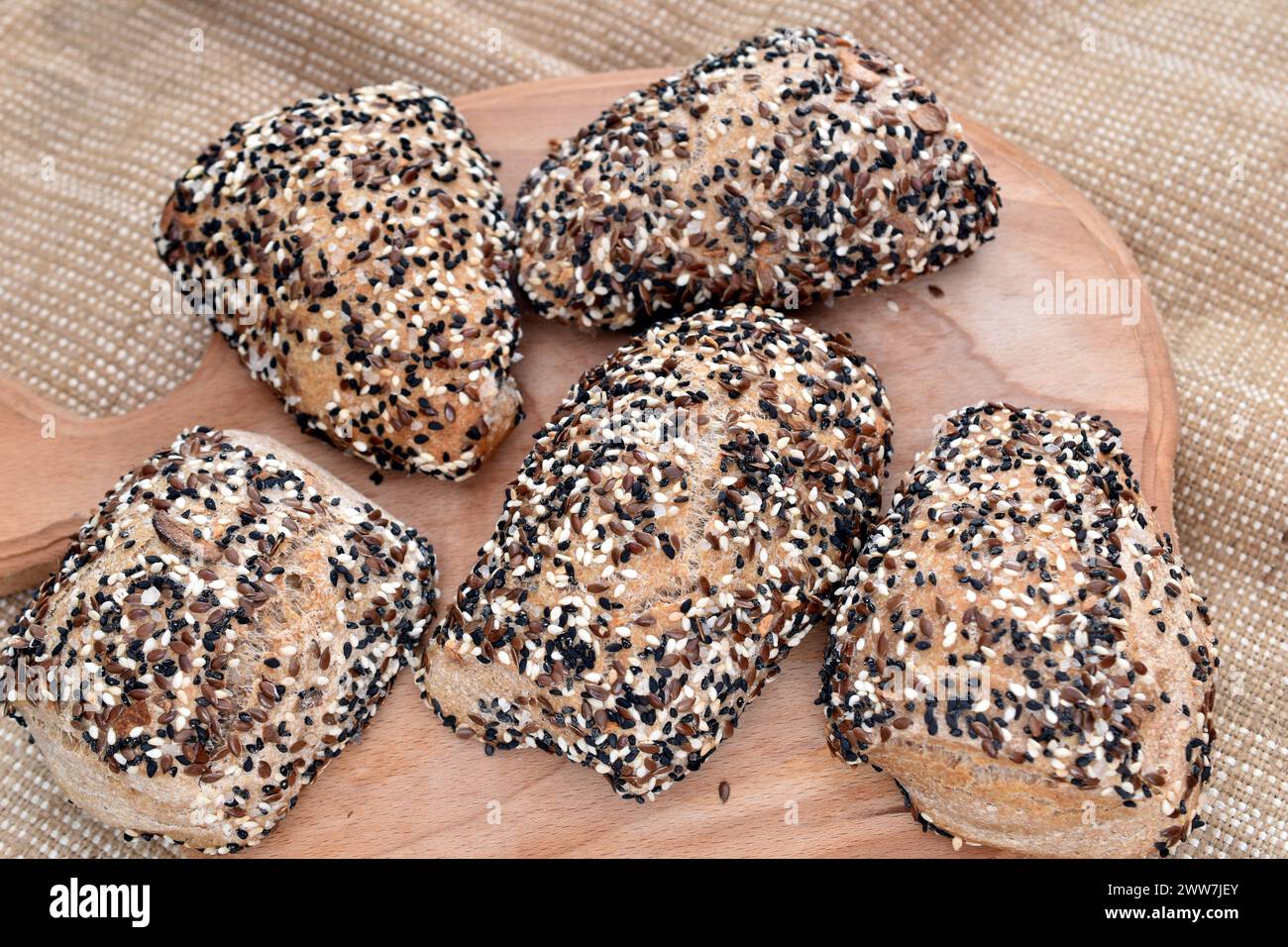 Diversi panini di pane, cotti a casa in forno e cosparsi di semi di lino, semi di sesamo e cumino. Foto Stock