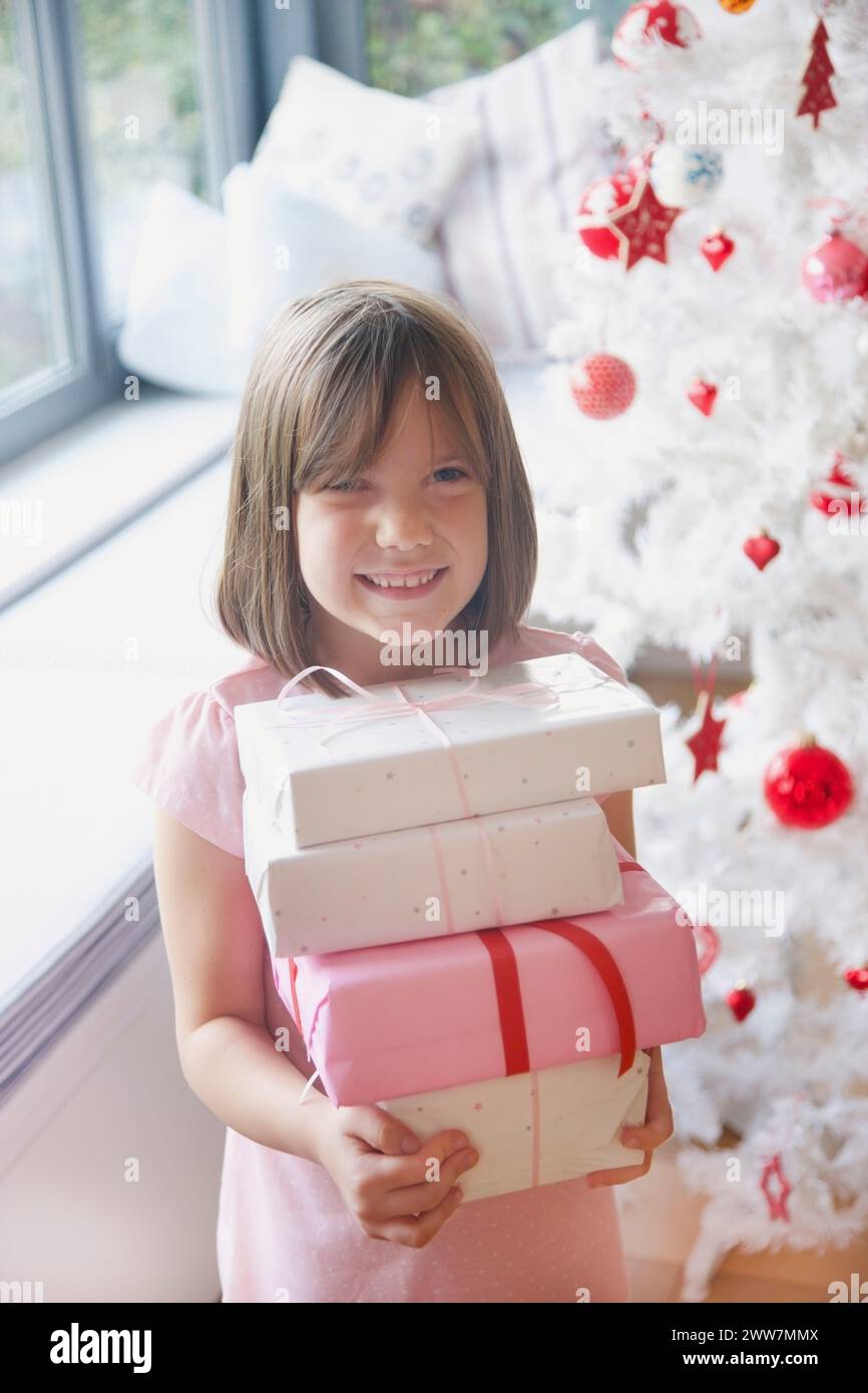 Sorridente ragazza giovane azienda pila di regali di Natale Foto Stock