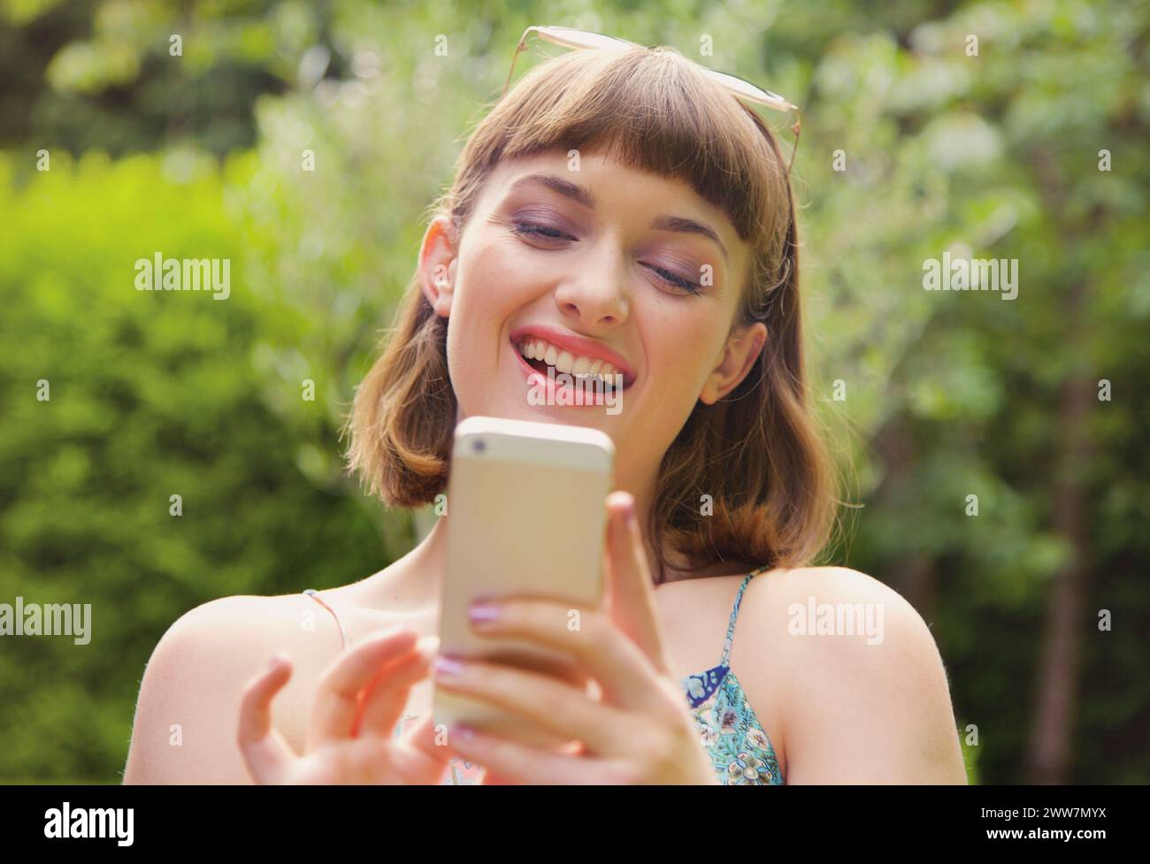 Sorridente ragazza adolescente che usa lo smartphone all'aperto Foto Stock