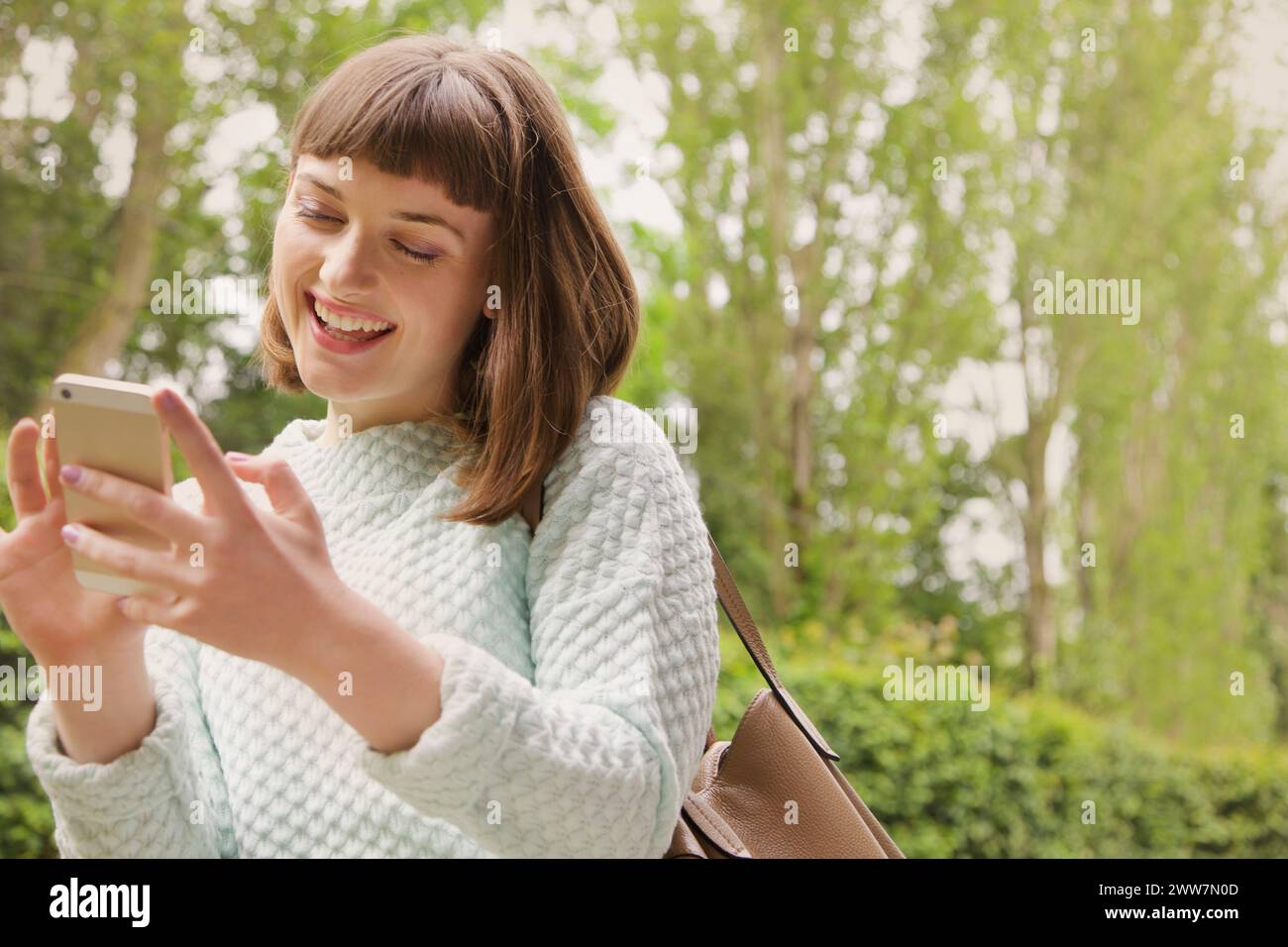 Sorridente ragazza adolescente che usa lo smartphone all'aperto Foto Stock