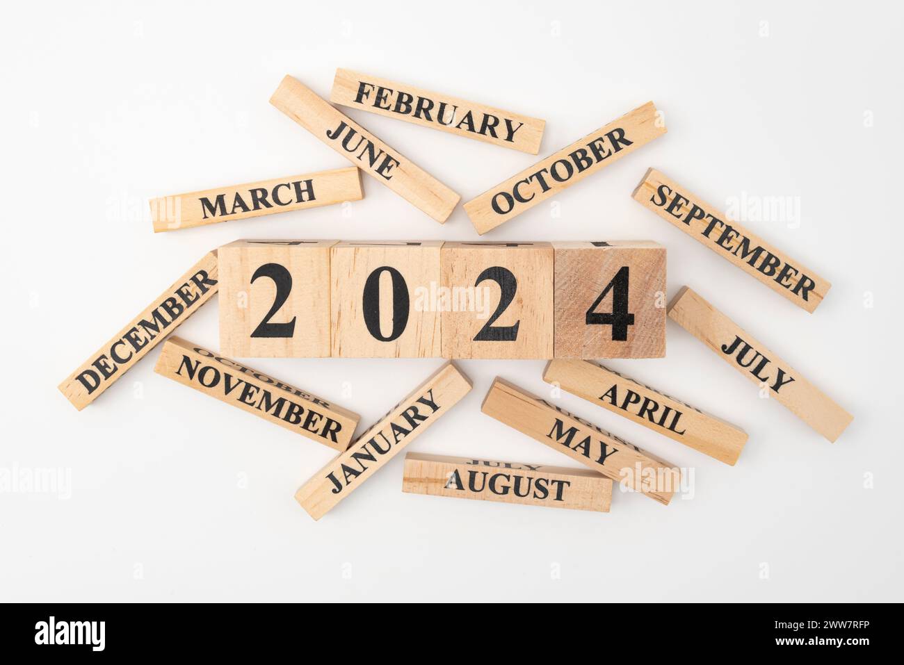 Blocchi di legno e cubetti con l'anno 2024 e i 12 mesi dell'anno sparpagliati casualmente. Isolato su sfondo bianco. Foto Stock
