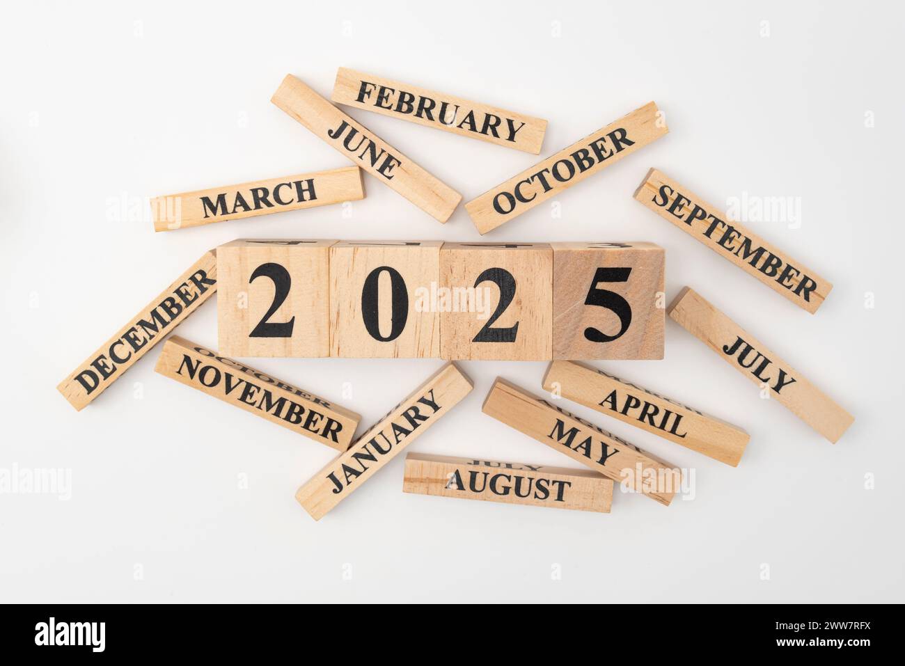 Blocchi di legno e cubetti con l'anno 2025 e i 12 mesi dell'anno sparpagliati casualmente. Isolato su sfondo bianco. Foto Stock