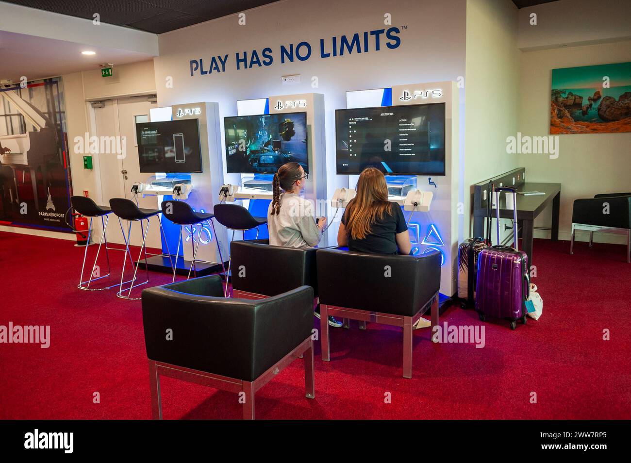 Aeroporto di Orly, Francia, ampie vedute interne, giovani in viaggio, due giovani amiche che giocano ai videogiochi in sala d'attesa da dietro, volo Foto Stock