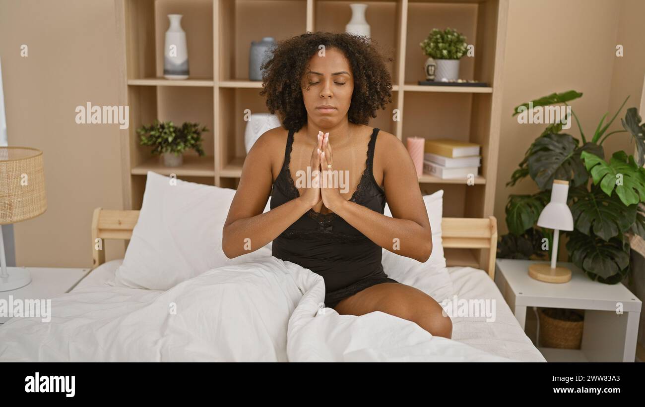 Donna afroamericana che meditava in camera da letto Foto Stock