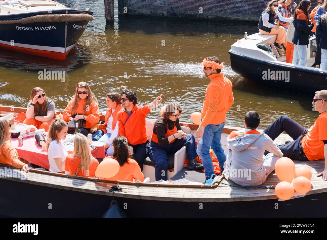 Gli amici potranno godersi il King's Day su una barca sul canale. Indossano un arancione brillante, salutando e applaudendo nella soleggiata Amsterdam - Paesi Bassi, Amsterdam, 27.04.2023 Foto Stock