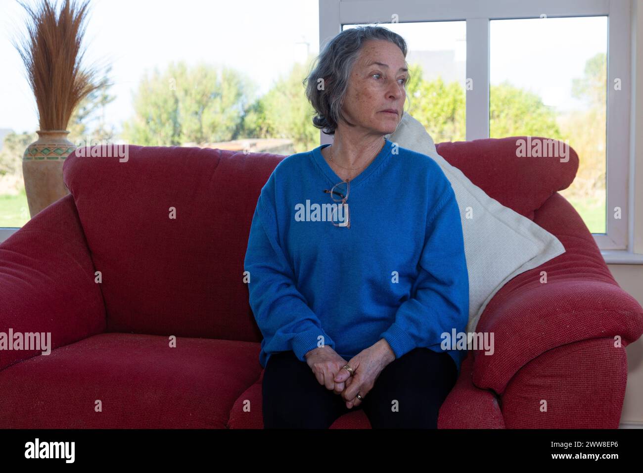 Donna anziana sola di divano Foto Stock