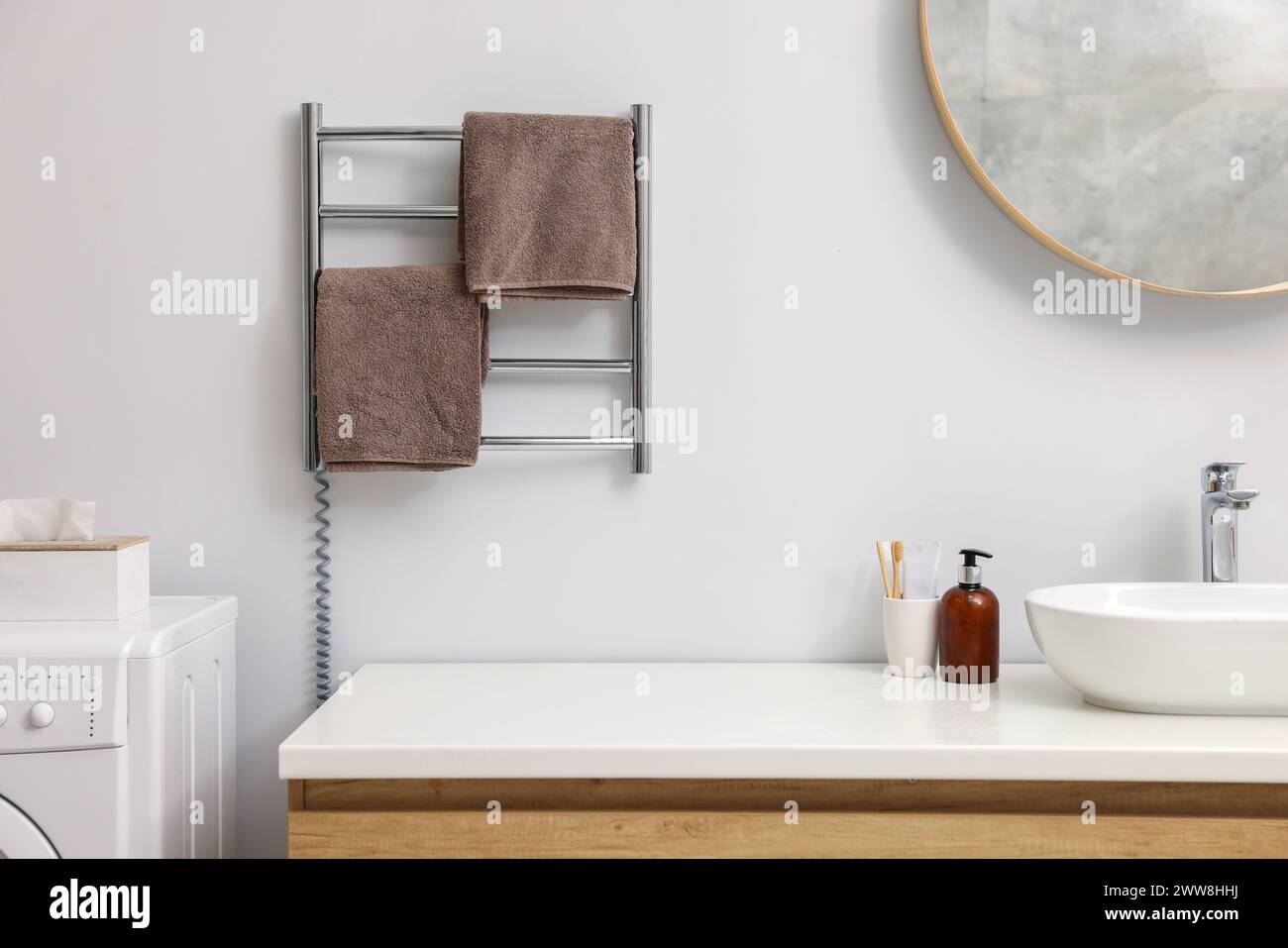 Portasciugamani riscaldato con asciugamani marroni in bagno Foto Stock