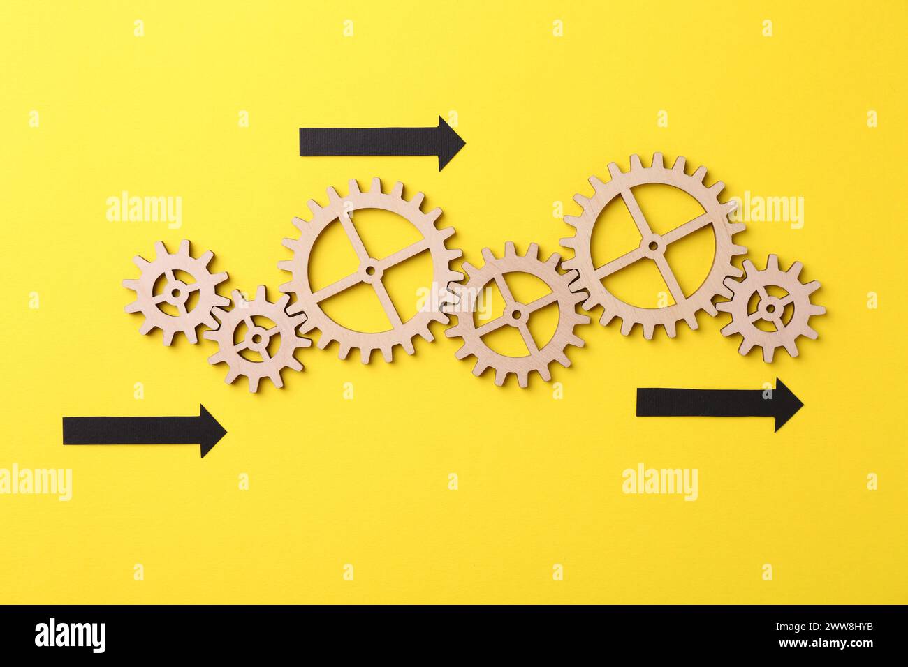 Organizzazione e ottimizzazione dei processi aziendali. Schema con figure in legno e frecce su sfondo giallo, vista dall'alto Foto Stock
