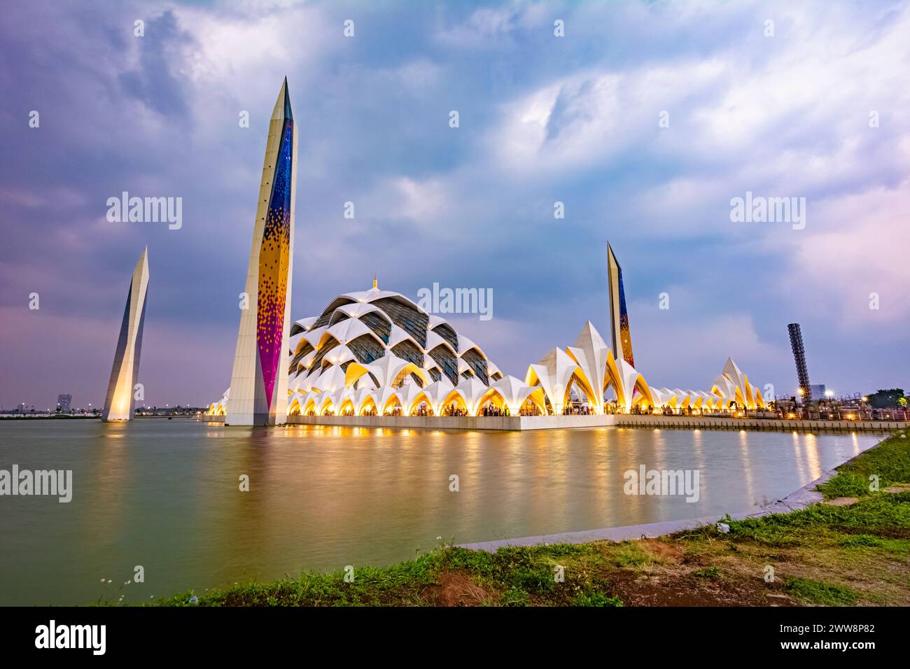 Bandung, Indonesia - 4 novembre 2023: Grande Moschea al Jabbar al tramonto (ora d'oro) con lampade e riflessi nello stagno Foto Stock