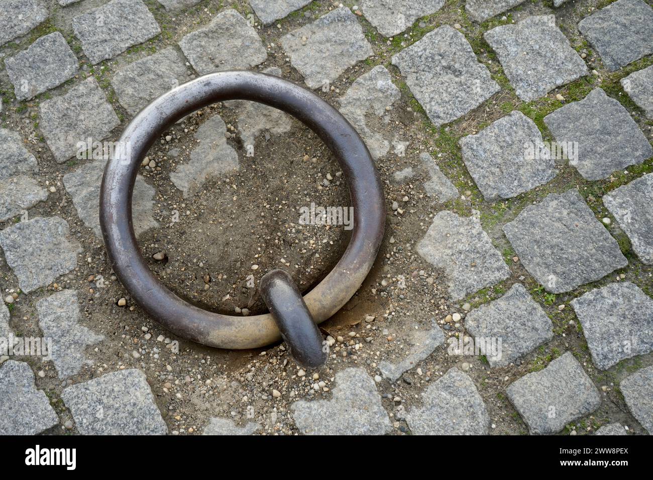 Anello di ormeggio in ferro rustico e resistente agli agenti atmosferici incorporato nella pavimentazione acciottolata. Foto Stock