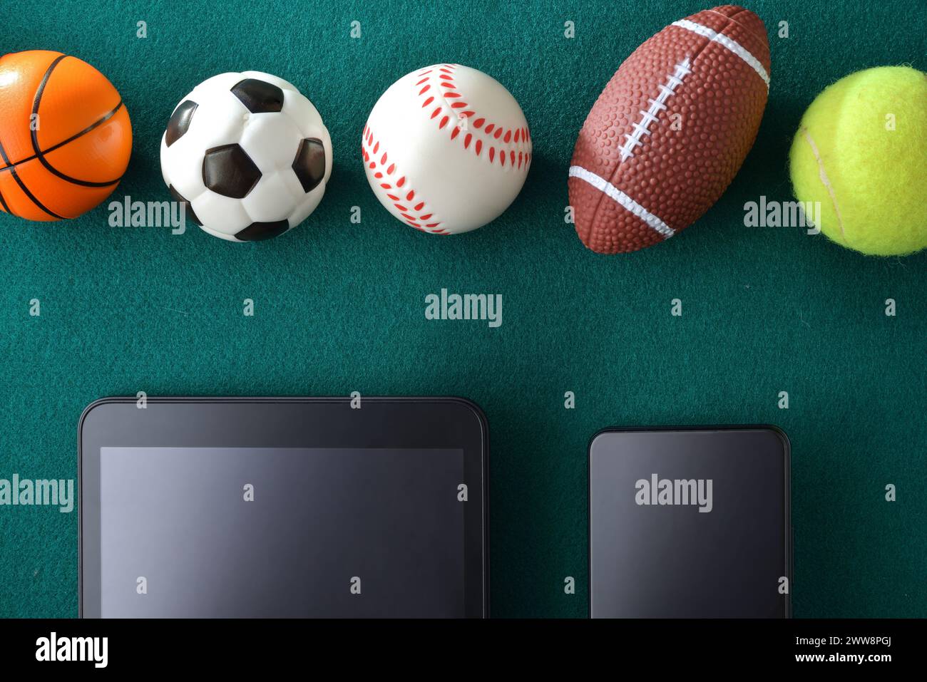 Concetto di eventi sportivi e tecnologia con tablet e smartphone allineati su feltro verde con palline di vari sport in fila. Vista dall'alto. Foto Stock