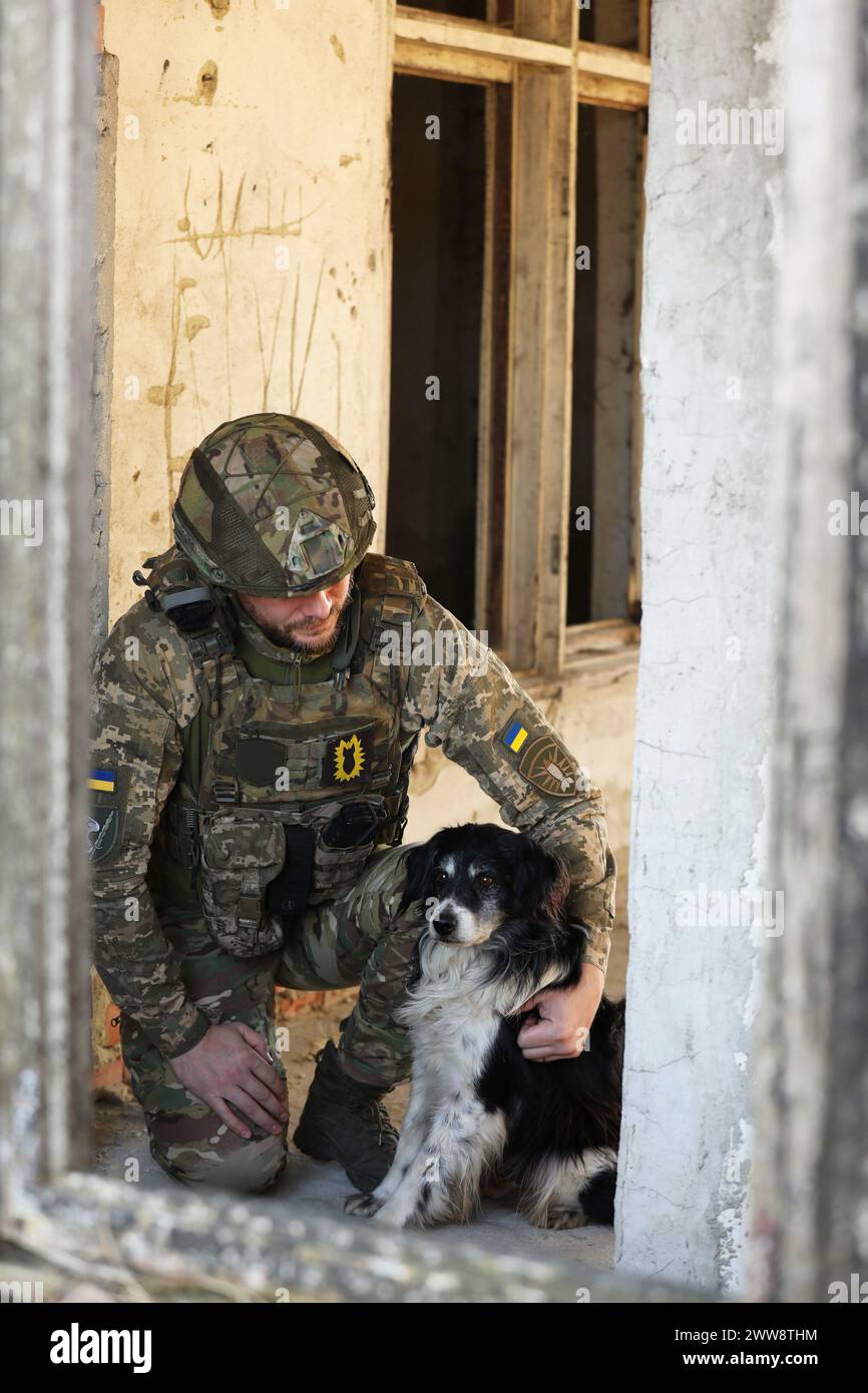 Soldato ucraino con cane randagio in un edificio abbandonato Foto Stock