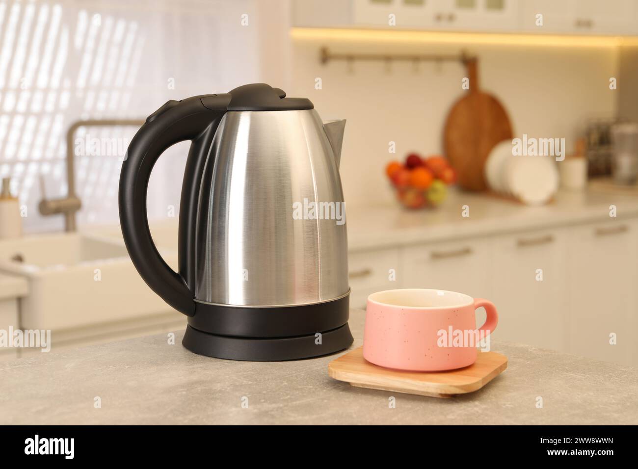 Bollitore elettrico e tazza sul tavolo in cucina Foto Stock