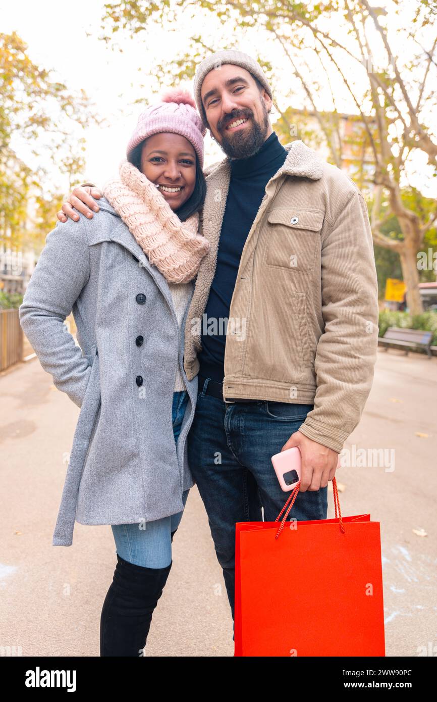 Coppia felice, sorriso ritratto e borse dello shopping in città insieme per moda, regalo o acquisto. Verticale Foto Stock