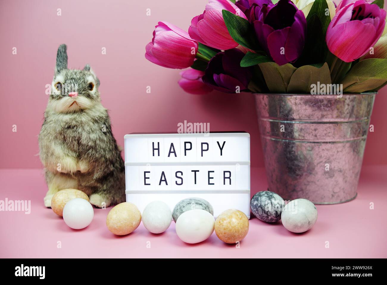 Scatola luminosa di buona Pasqua con decorazione degli elementi pasquali su sfondo rosa Foto Stock