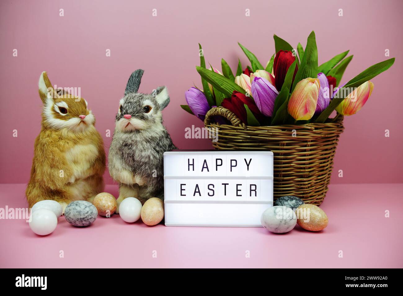 Scatola luminosa di buona Pasqua con decorazione degli elementi pasquali su sfondo rosa Foto Stock