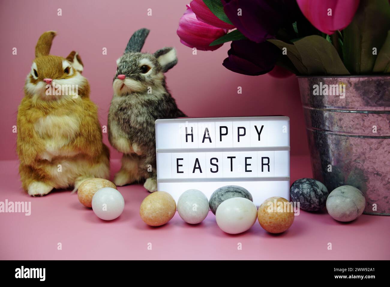 Scatola luminosa di buona Pasqua con decorazione degli elementi pasquali su sfondo rosa Foto Stock