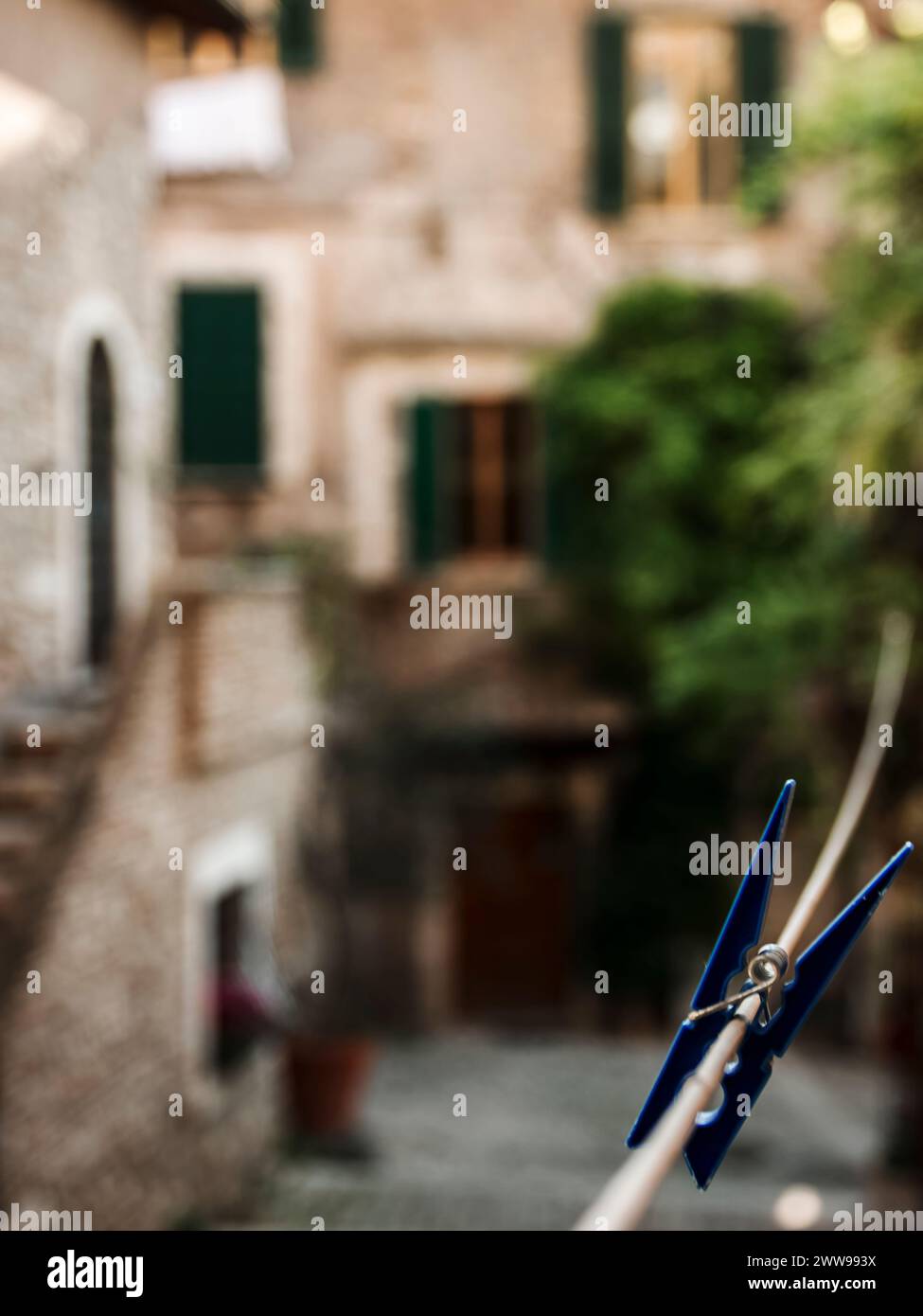 Un clothespin blu, lasciato attaccato alla corda in attesa di essere utilizzato per asciugare i vestiti, nella splendida cornice di un tipico borgo medievale italiano Foto Stock