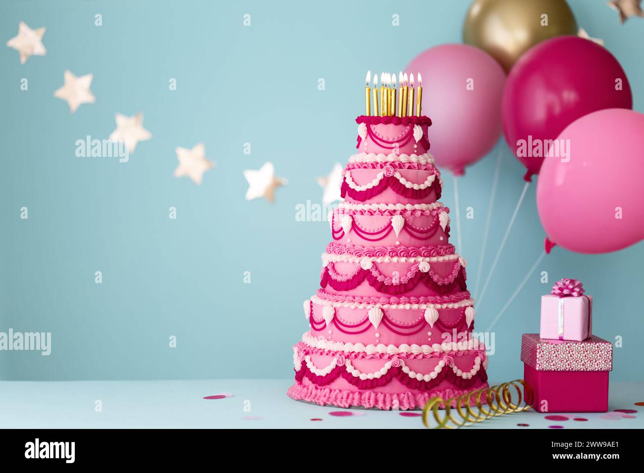 Elaborata torta di compleanno rosa a più livelli con regali e palloncini di compleanno per una festa di compleanno Foto Stock