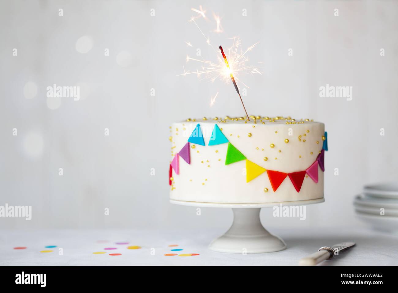 Torta di compleanno per festeggiare con coloratissimi mazzetti arcobaleno e un allegro sparkler Foto Stock