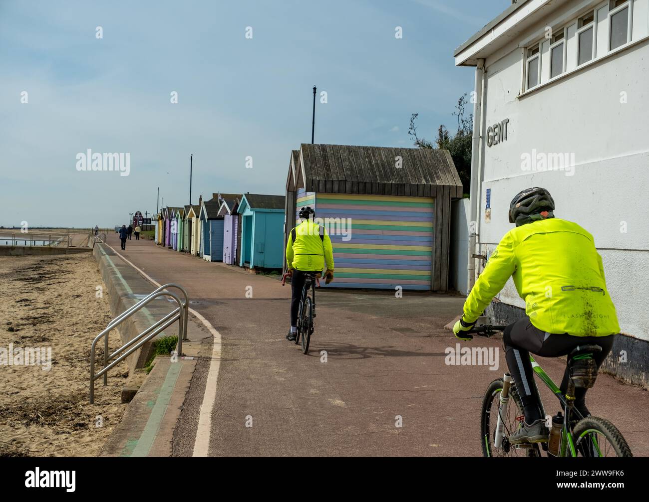 Clacton-on-Sea, Essex, Regno Unito – marzo 2024. Due ciclisti in alta visibilità in bicicletta lungo la passeggiata nella città costiera di Clacton-on-Sea, Essex Foto Stock