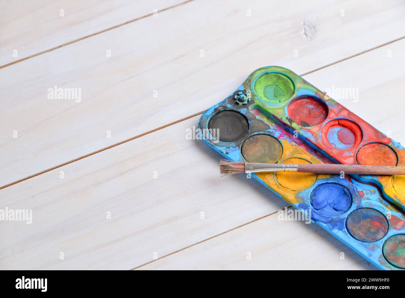 Pennello rustico e acquerelli in primo piano su un tavolo da lavoro in legno. Perfetto per temi artistici o concetti di pittura Foto Stock