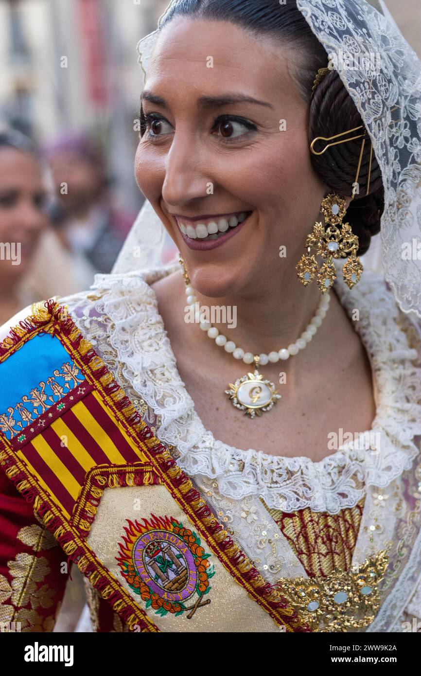 Il vivace costume di a Fallera, adornato con fili dorati, cattura lo spirito festivo di Gandia. Il suo velo di pizzo e la collana di perle incarnano l'eleganza di Foto Stock