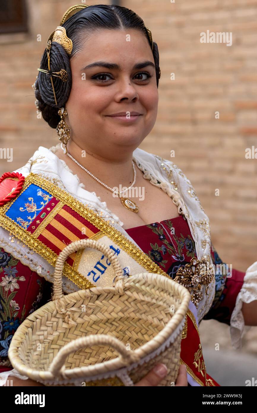 Eleganza valenciana a schermo intero. L'abbigliamento di un Fallera, ricco di rosso e bianco con accenti dorati, cattura lo spirito del festival Fallas di Gandia. Foto Stock