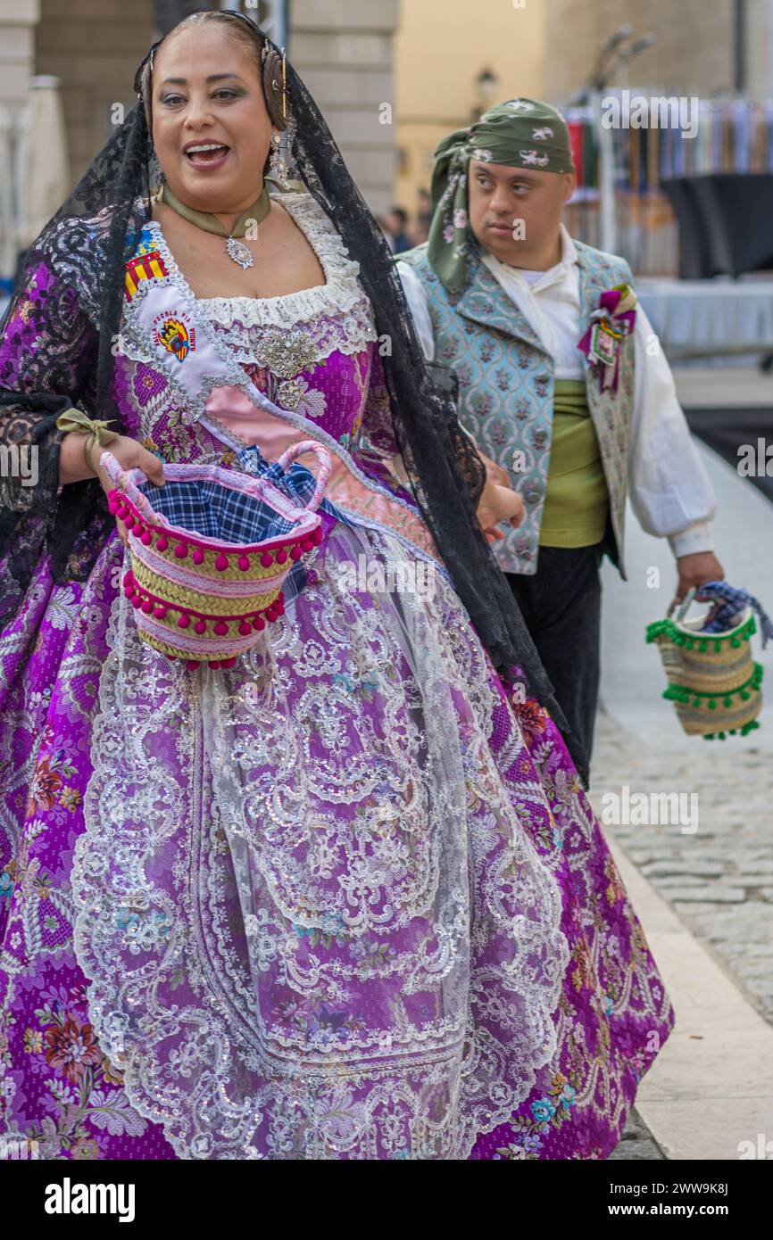 Donna in abbigliamento tradizionale con cesto di fiori incarna lo spirito festivo di Valencia. Fallas Festival a Gandia Spagna Una celebrazione della cultura. Foto Stock