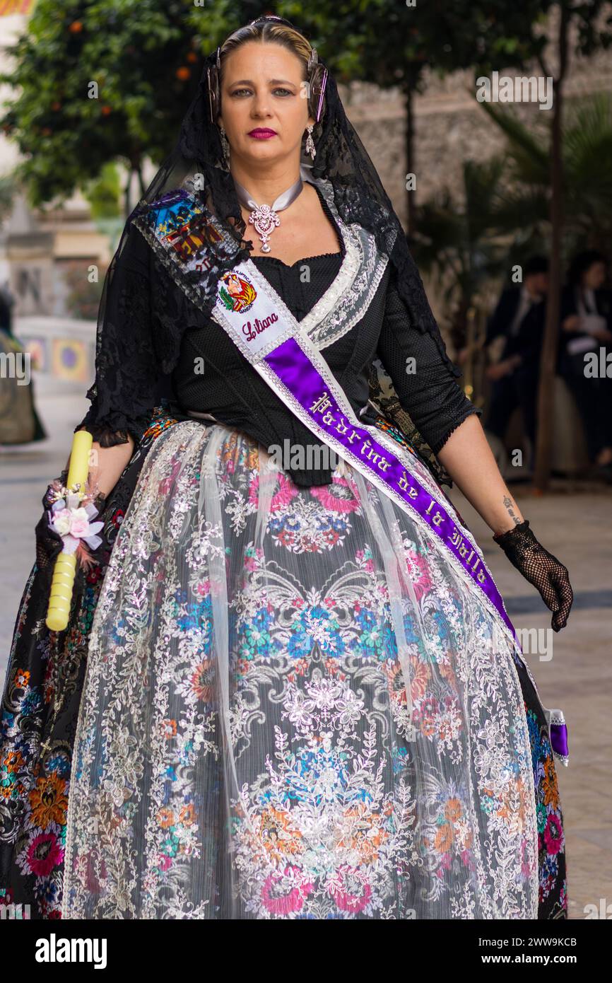 Un arazzo di tradizione, una donna in costume Fallas si erge come un vibrante emblema del patrimonio di Gandia. Il suo abbigliamento, un caleidoscopio di colori e motivi, Foto Stock