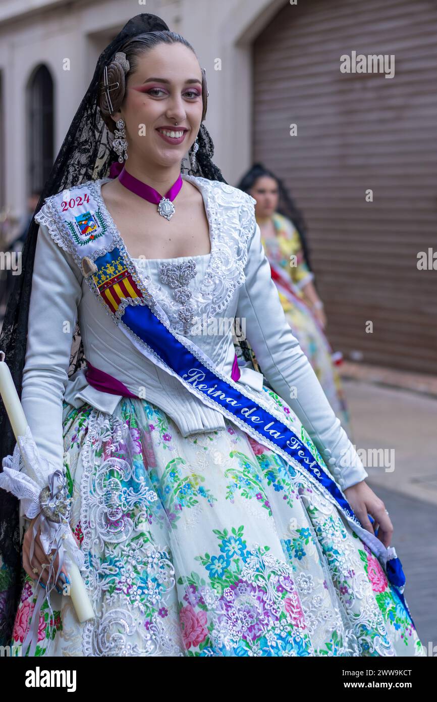 L'abito tradizionale di una donna fiorisce con colori vivaci e disegni intricati nelle feste di Gandia. Il suo abbigliamento, una testimonianza del ricco cultu di Valencia Foto Stock