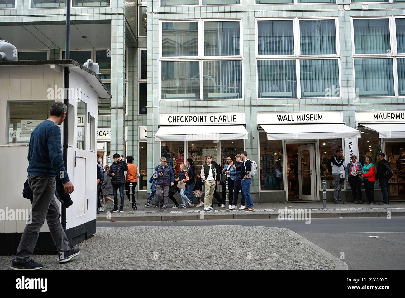 La strada nel settore americano al Checkpoint Charlie, che è il posto di controllo degli Stati Uniti dopo la seconda guerra mondiale, che vanta negozi di souvenir mentre la gente passeggia, Berlino, Germania Foto Stock