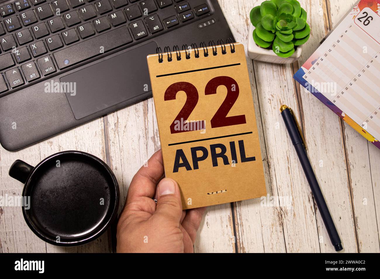 Calendario in legno su banco in legno mostra la data del 22 aprile, giorno della terra con sfondo naturale Foto Stock