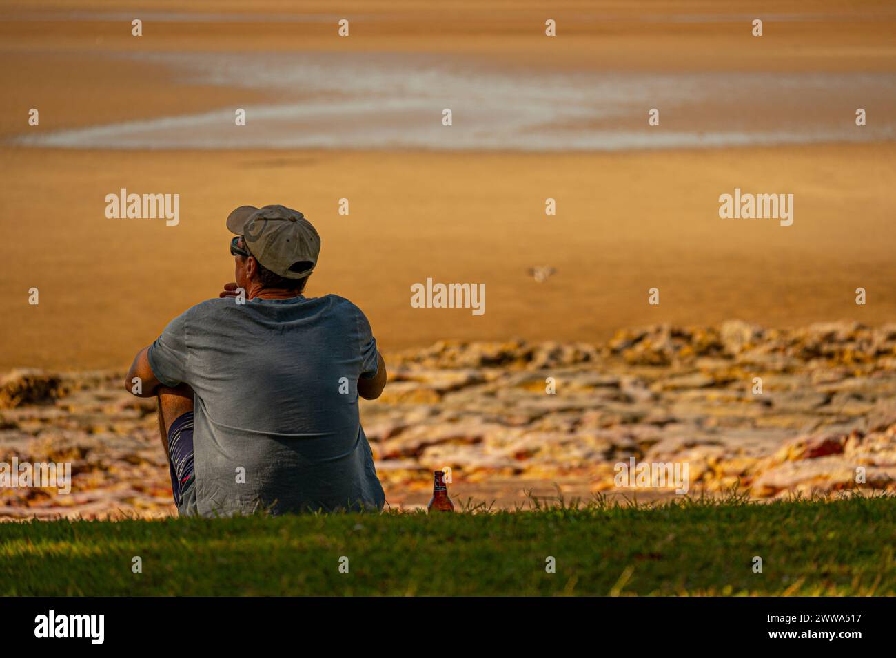 Una figura solitaria trova conforto in riva al mare, un momento personale contro la vastità della natura. Foto Stock