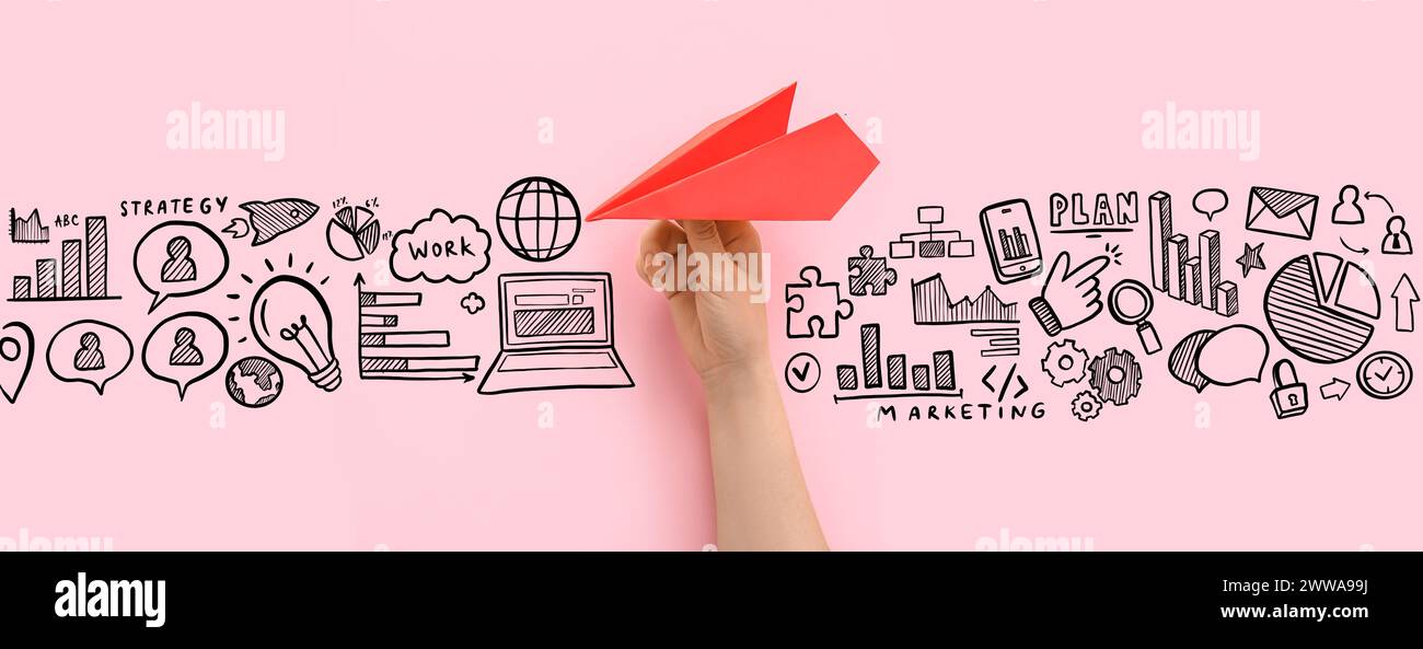 Mano con la pialla di carta e icone disegnate su sfondo rosa. Concetto di strategia di marketing Foto Stock