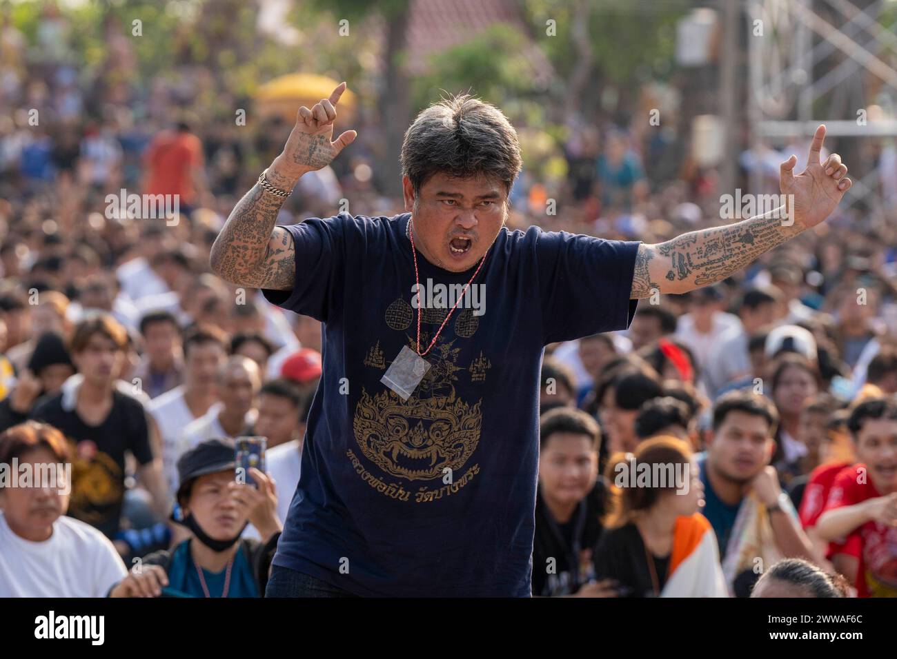 Nakhon Pathom, Thailandia. 23 marzo 2024. I devoti che hanno avuto sacri tatuaggi di sak yant cadono in uno stato di possesso e violenze verso il tempio durante la cerimonia annuale di Wai Kru a Wat Bang Phra a Nakhon Pathom, Thailandia. Tempio di Wat Bang Phra, a 40 km dalla capitale tailandese Bangkok, ospita la cerimonia Wai Gru una volta all'anno. Il nome dei templi si traduce come Monastero della Riverbank Buddha Image. I tatuaggi Sak Yant sono tatuaggi altamente stilizzati di preghiere buddiste e simboli religiosi, pensati per portare una protezione speciale e altri benefici ai fedeli che li fanno mettere sul loro corpo. Foto Stock