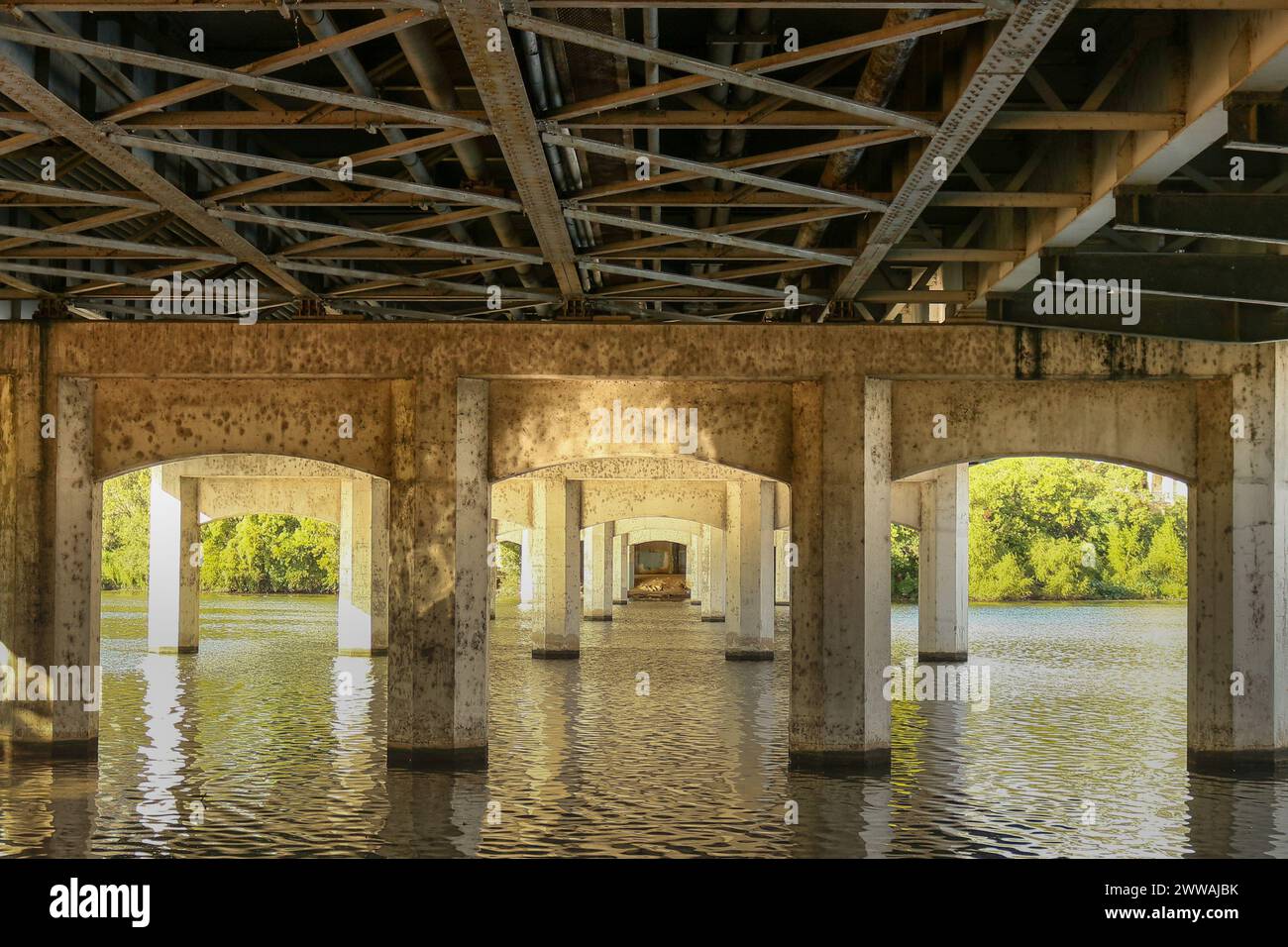 Sotto il 1st Street Bridge di Austin, Texas, l'aspra bellezza del design industriale incontra la serenità naturale del fiume Colorado. Il suppo Foto Stock